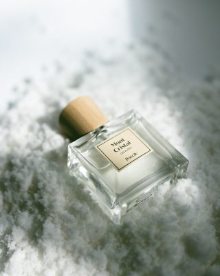 Chai nước hoa thuần chay Poécile Mont Cristal Les Alpes nắp gỗ nghiêng nhẹ trong lớp tuyết trắng tinh khôi.